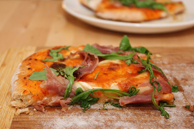 ein Stück hausgemachte Pizza mit Schinken, Rauke und Mozzarella