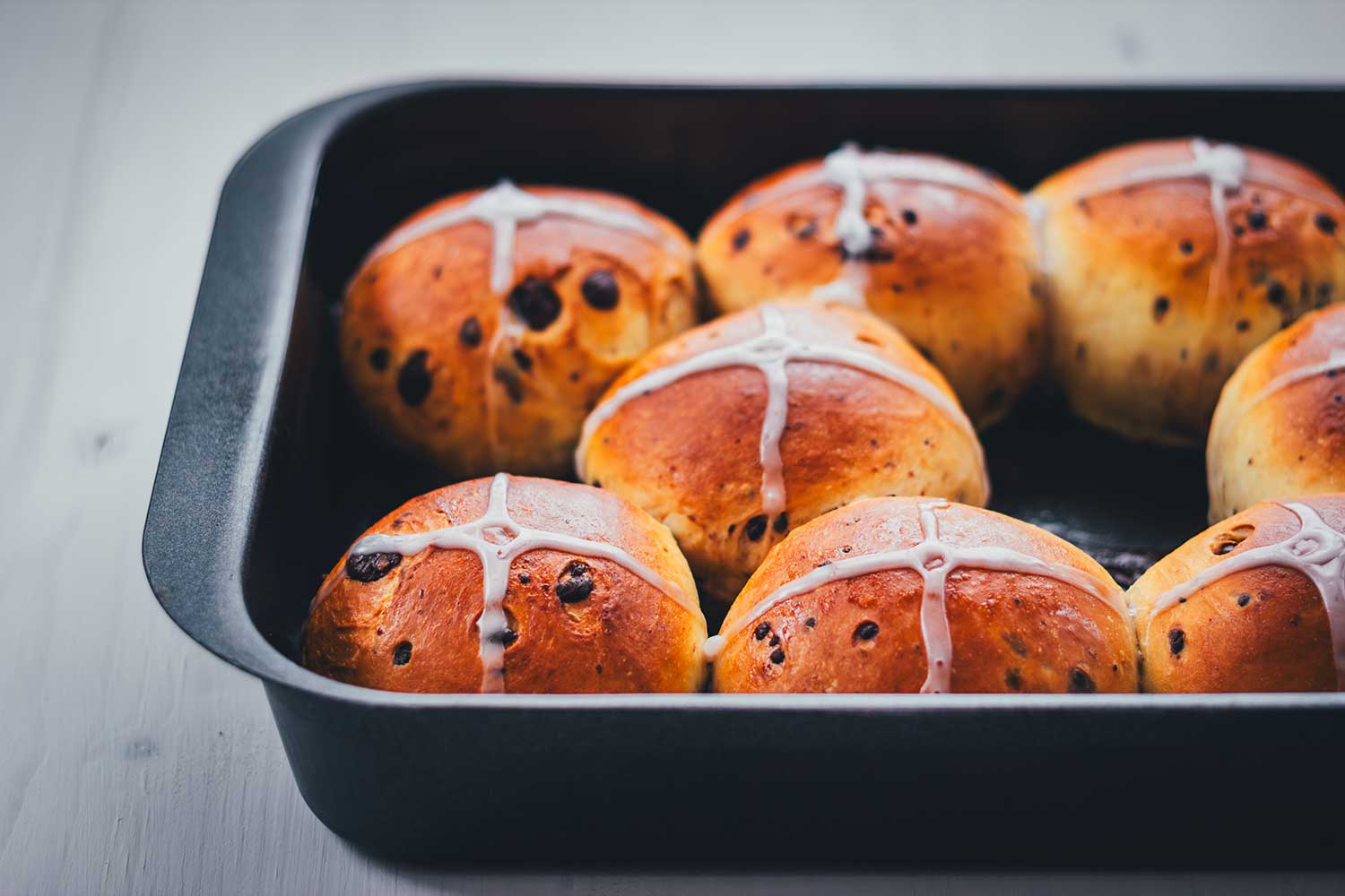 Ansicht von einer Backform, gefüllt mit fluffigen Schokobrötchen, als Hot Cross Buns mit Zuckerguss gebacken
