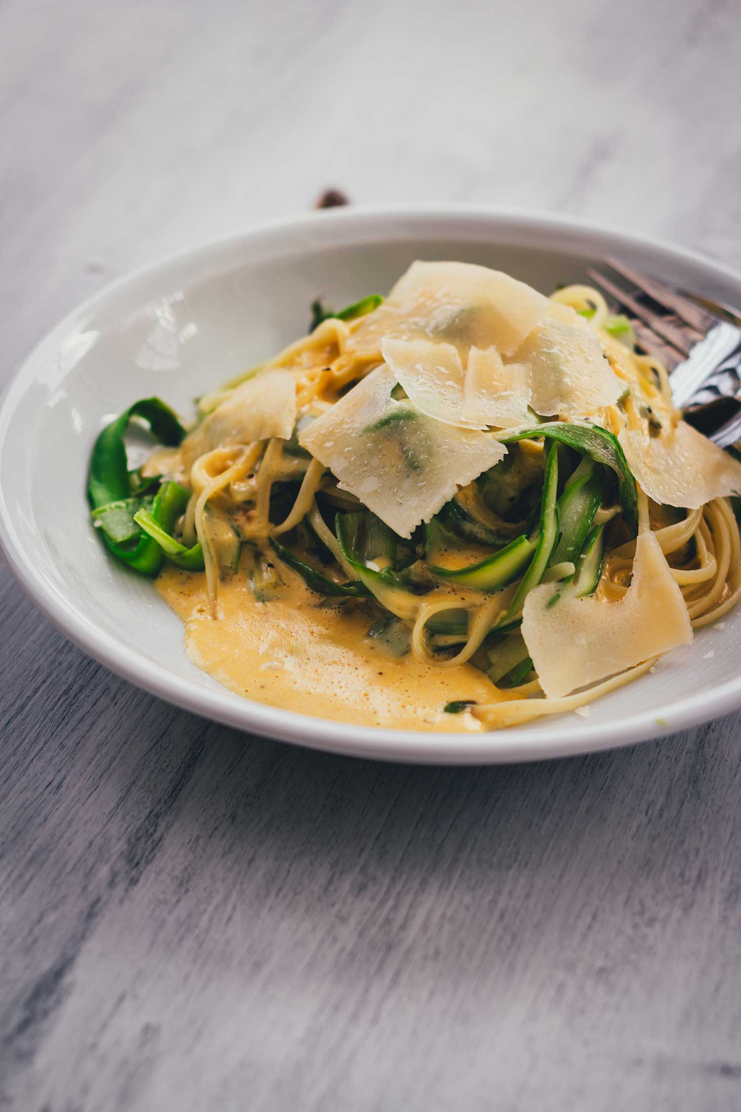 Teller mit Linguine mit grünem Spargel und Parmesansauce serviert.