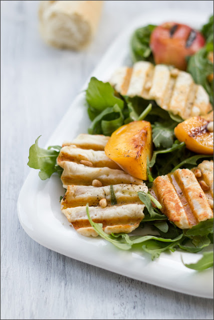 Sommersalat mit Halloumi-Chips und gegrillten Pfirsichen auf einer Platte angerichteter Sommersalat mit knusprigen Halloumi-Chips und gegrillten Pfirsichen
