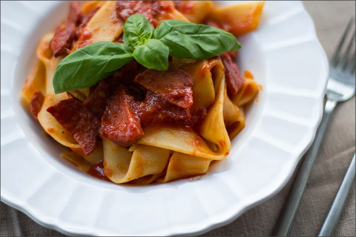 Pasta mit Chorizo-Tomatensauce Angerichtete Pappardelle mit Chorizo-Tomatensauce und Basilikum serviert