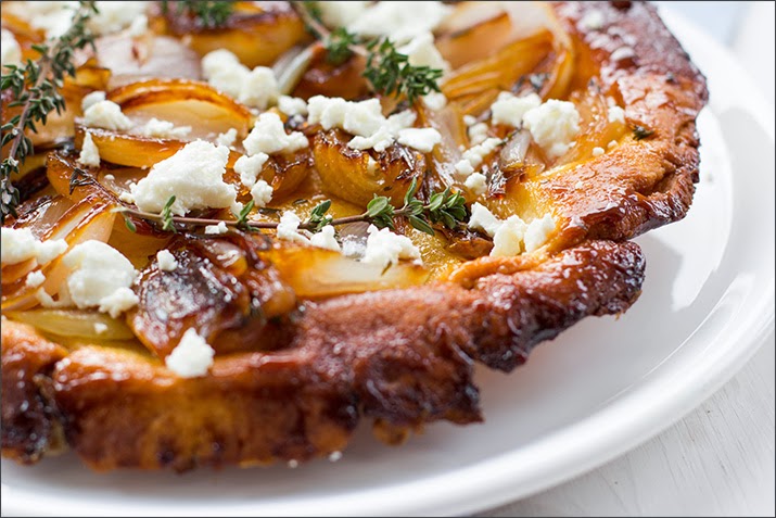 Schalotten-Tarte-Tatin aus Mürbeteig mit Thymian und Feta Tarte Tatin mit karamellisierten Schalotten, Thymian und zerkrümeltem Feta auf einer Servierplatte