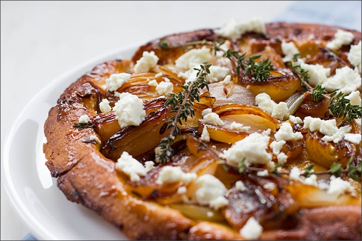 Schalotten-Tarte-Tatin aus Mürbeteig mit Thymian und Feta Tarte Tatin mit karamellisierten Schalotten, Thymian und zerkrümeltem Feta auf einer Servierplatte