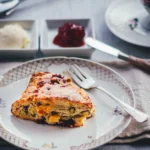 Himbeer Scones mit Pistazien und weißer Schokolade auf einem Goldrand-Teller, dazu Clotted Cream und Himbeerkonfitüre in kleinen Schälchen