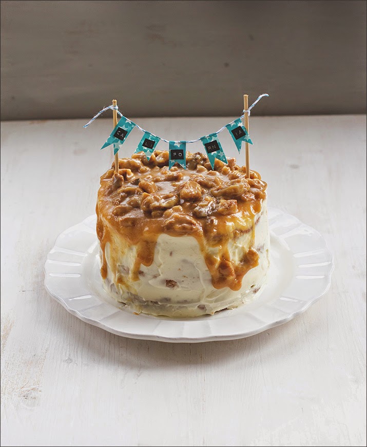 California-Walnuss-Törtchen mit Cream-Cheese-Frosting und Walnuss-Karamell 4-stöckiges Walnuss-Biskuit-Törtchen mit Frischkäsefrosting, mit Wimpelgirlande auf einem Teller