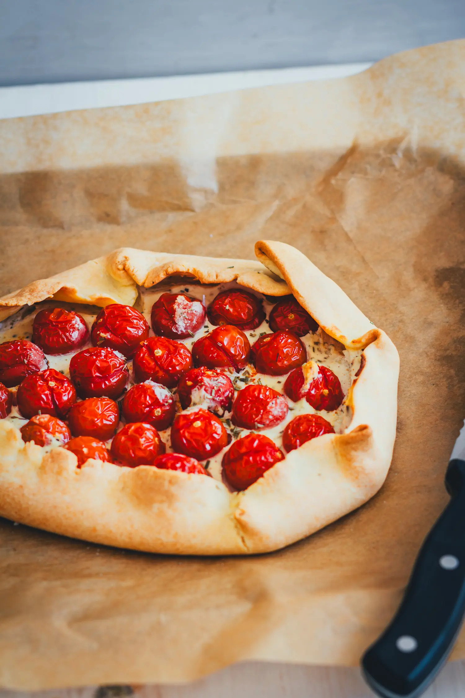 Ganze Tomaten-Galette mit umgeklapptem Teigrand, dicht belegt mit gebackenen Kirschtomaten