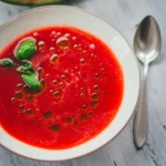Cremige Wassermelonen-Gazpacho mit Olivenöl-Tropfen und Basilikum, von oben fotografiert