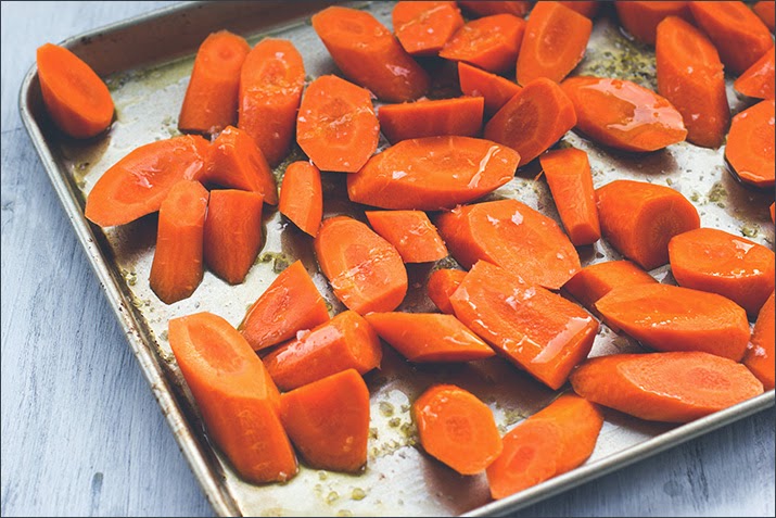 Möhrenstücke mit Olivenöl und Meersalz auf dem Backblech - geröstete Möhren für eine vegetarische Möhrensupper Möhrenstücke mit Olivenöl und Meersalz auf dem Backblech - geröstete Möhren für eine vegetarische Möhrensupper