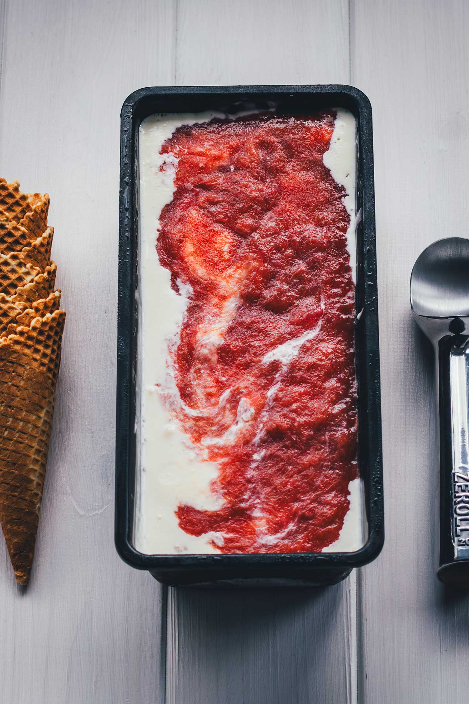 Frisch eingefülltes Rhabarber-Eis mit deutlich sichtbarer Marmorierung aus Frischkäse-Eis und Rhabarber-Kompott.