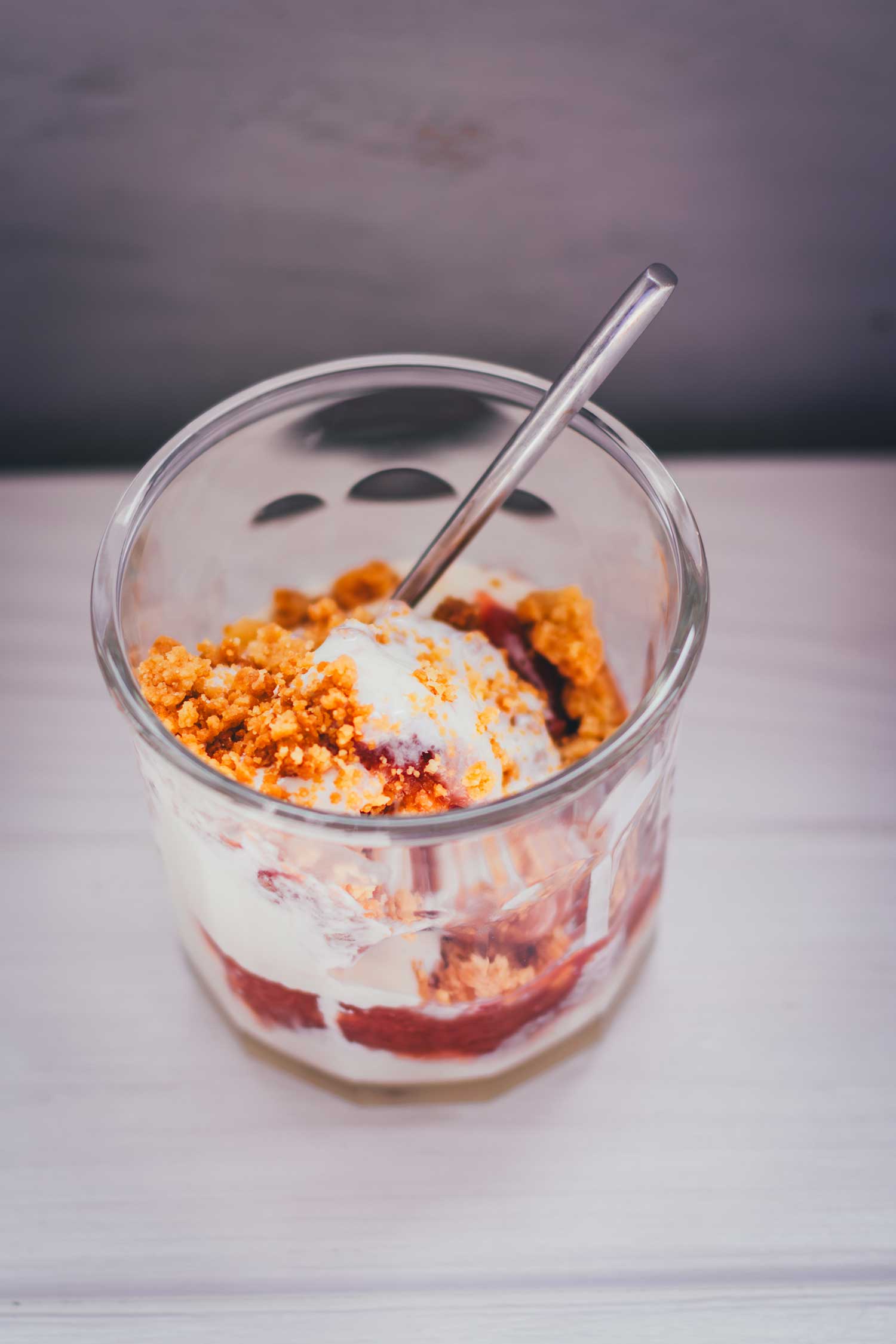 Rhabarber-Eis im Glas mit Streuseln serviert, fertiges Dessert mit Crumble-Topping
