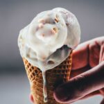 Rhabarber-Eis mit Streuseln auf einem Waffelkegel, von Hand gehalten