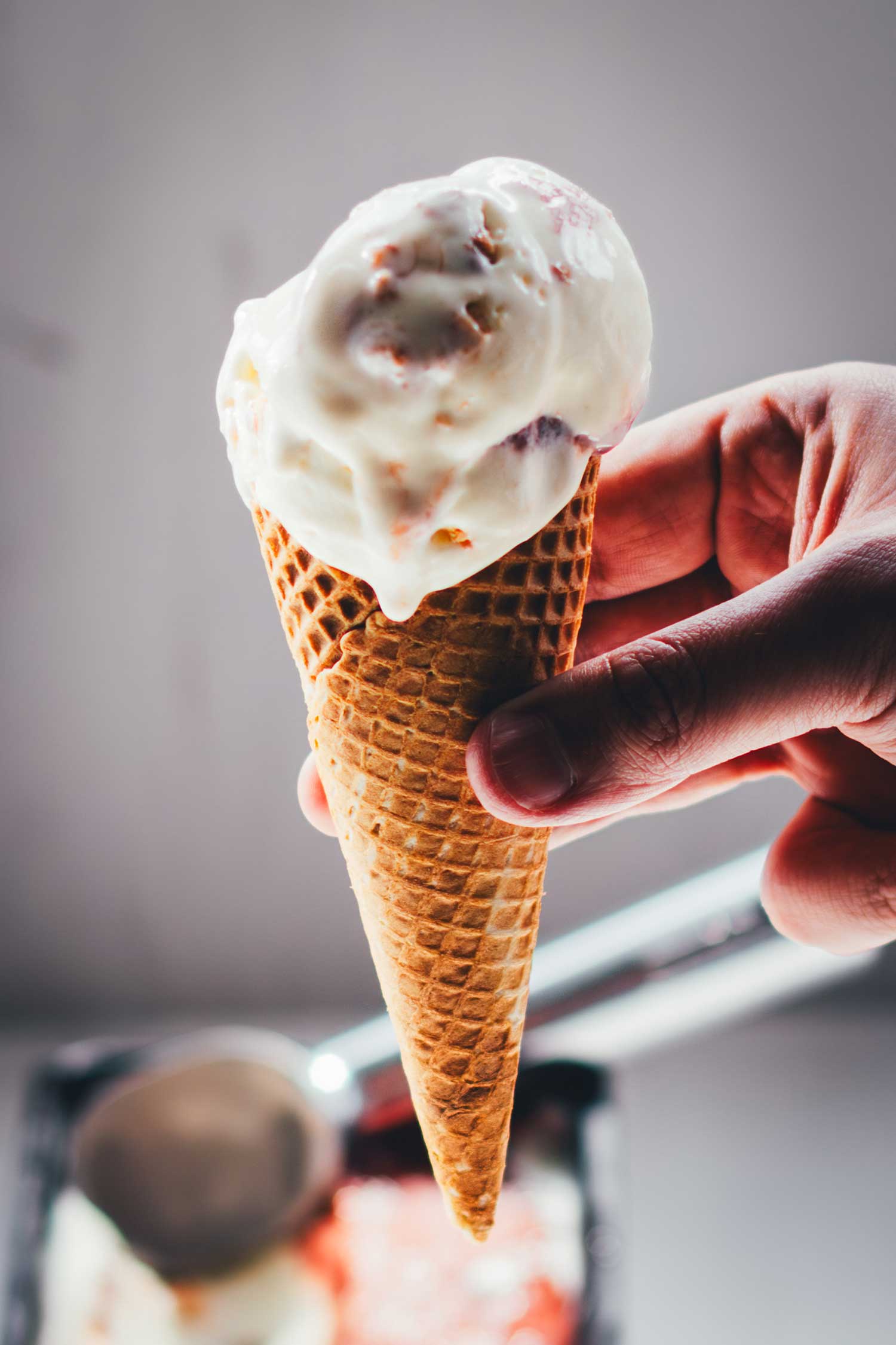Eiskugel Rhabarber-Eis mit Frischkäse-Note und Rhabarber-Marmorierung im Waffelhörnchen.