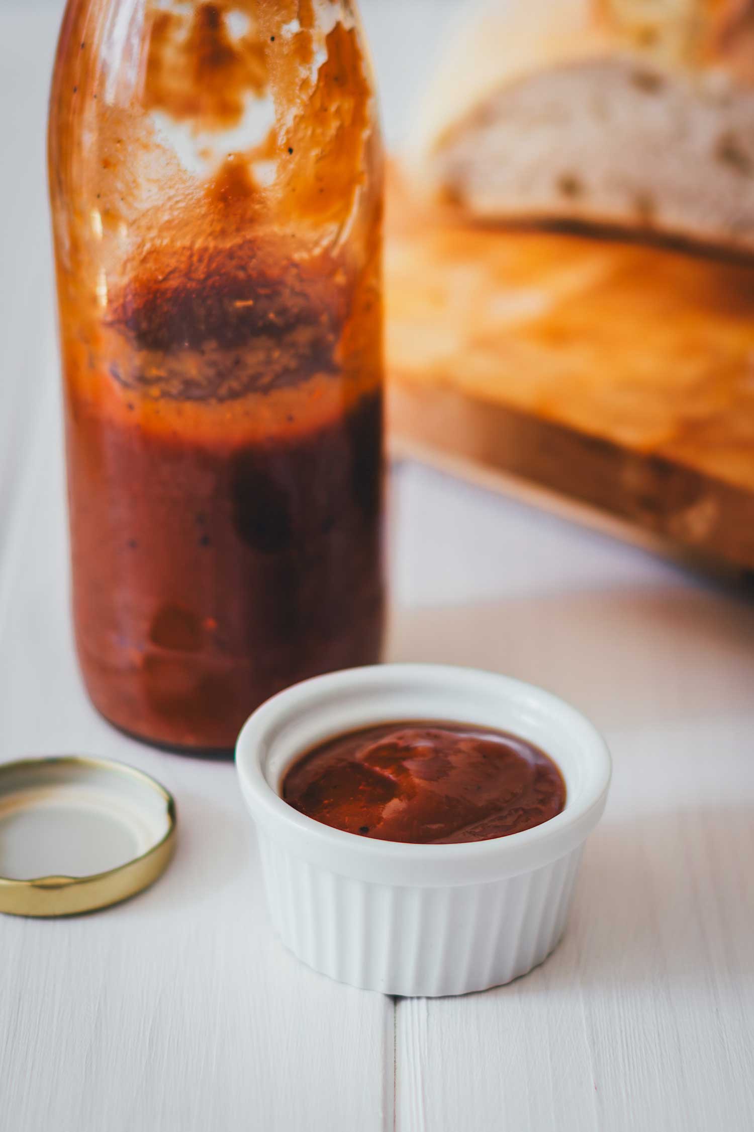 Süß-säuerliche Rhabarber-Grillsauce im weißen Schälchen serviert, daneben die fertige Flasche Rhabarberketchup