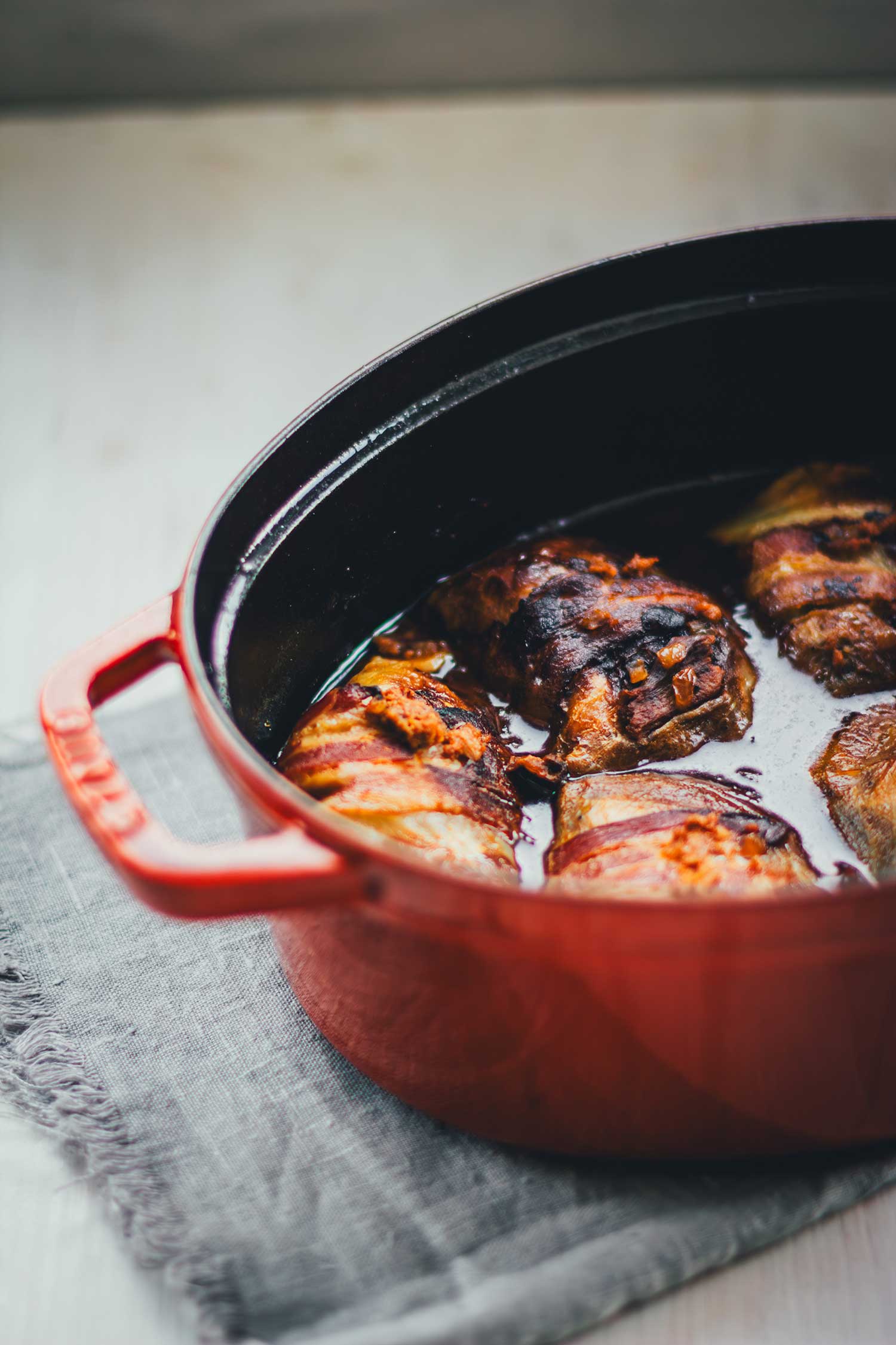Kohlrouladen im Bräter mit Speck umwickelt in dunkler Sauce