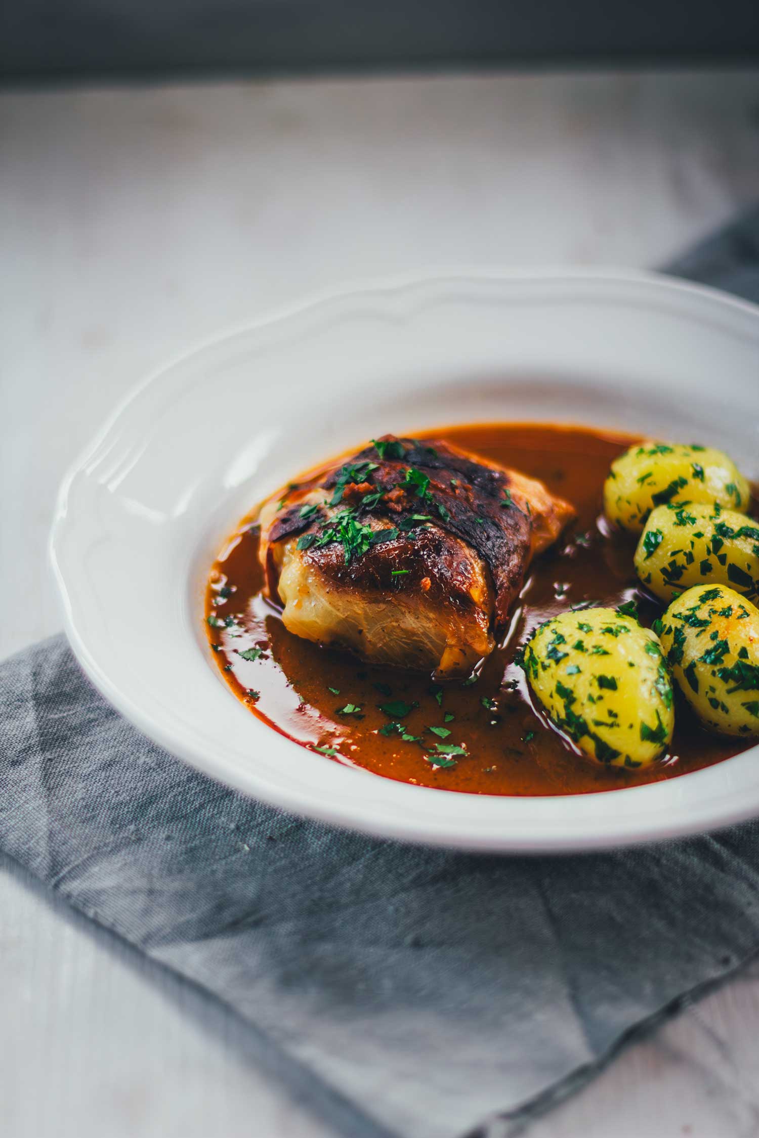 Kohlroulade mit Fleischfüllung in kräftiger Sauce auf weißem Teller