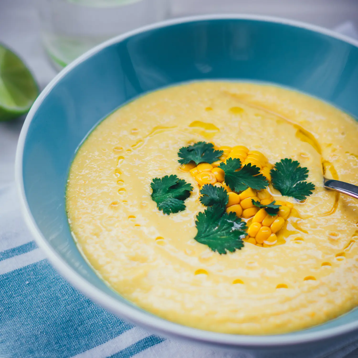 Nahaufnahme einer Schüssel, gefüllt mit kalter Mais-Paprika-Gazpacho, getoppt mit Maiskörnern und Koriander.
