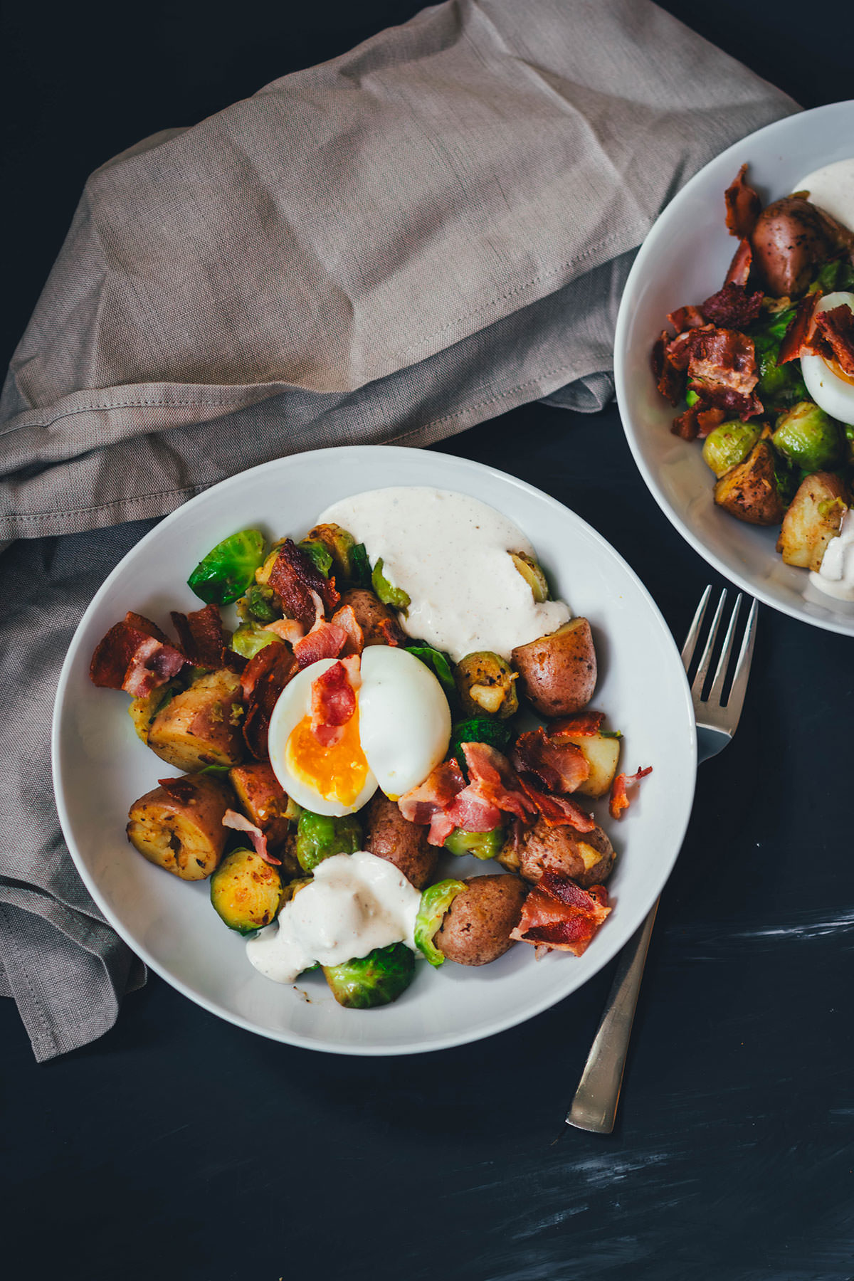 Hier teile ich mein Rezept für eine deftige Rosenkohl-Kartoffel-Pfanne. Serviert mit wachsweichem Ei, knusprigem Bacon und würzigem Knoblauch-Schmand. Perfekt für die schnelle Feierabendküche in Herbst und Winter! | moeyskitchen.com