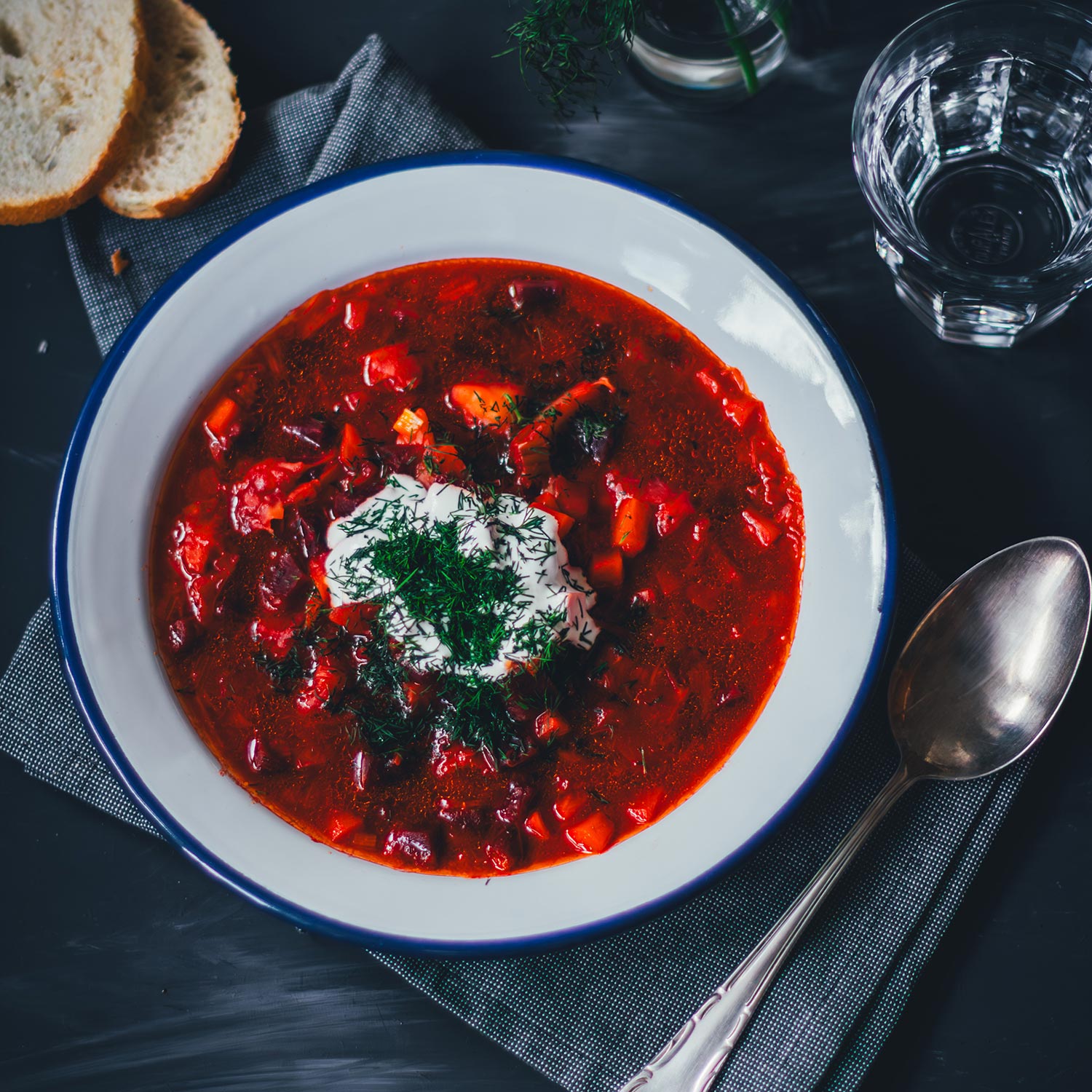 Topshot eines Tellers mit einer Portion Borschtsch (Borscht). Getoppt mit Saurer Sahne und Dill und mit etwas Brot serviert. | moeyskitchen.com