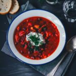 Topshot von einem Teller Borschtsch (Borscht), serviert mit Saure Sahne, Dill und Brot | moeyskitchen.com