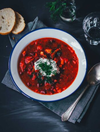 Topshot von einem Teller Borschtsch (Borscht), serviert mit Saure Sahne, Dill und Brot | moeyskitchen.com