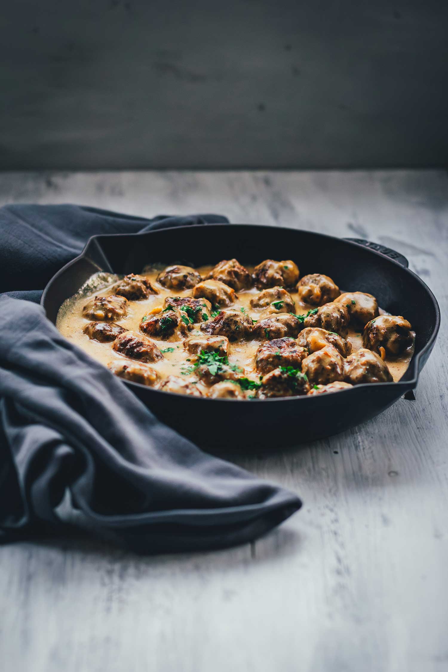 Seitliche Ansicht einer gusseisernen Pfanne, servierbereit gefüllt mit Köttbullar in Sauce | moeyskitchen.com