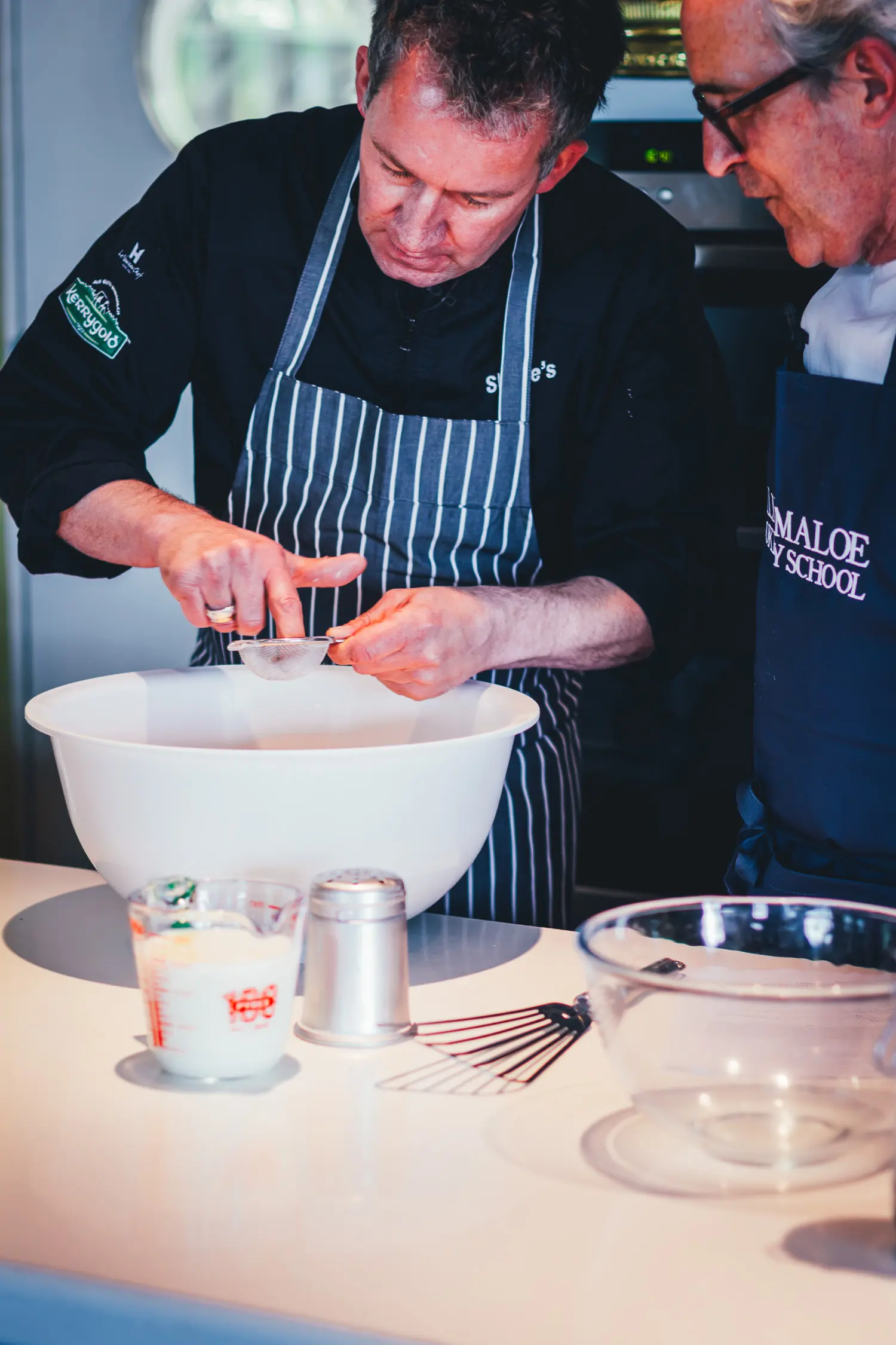 Rory O'Connell und Koch Shane McMahon sieben Mehl beim Zubereiten der irischen Scones in der Showküche der Ballymaloe Cookery School