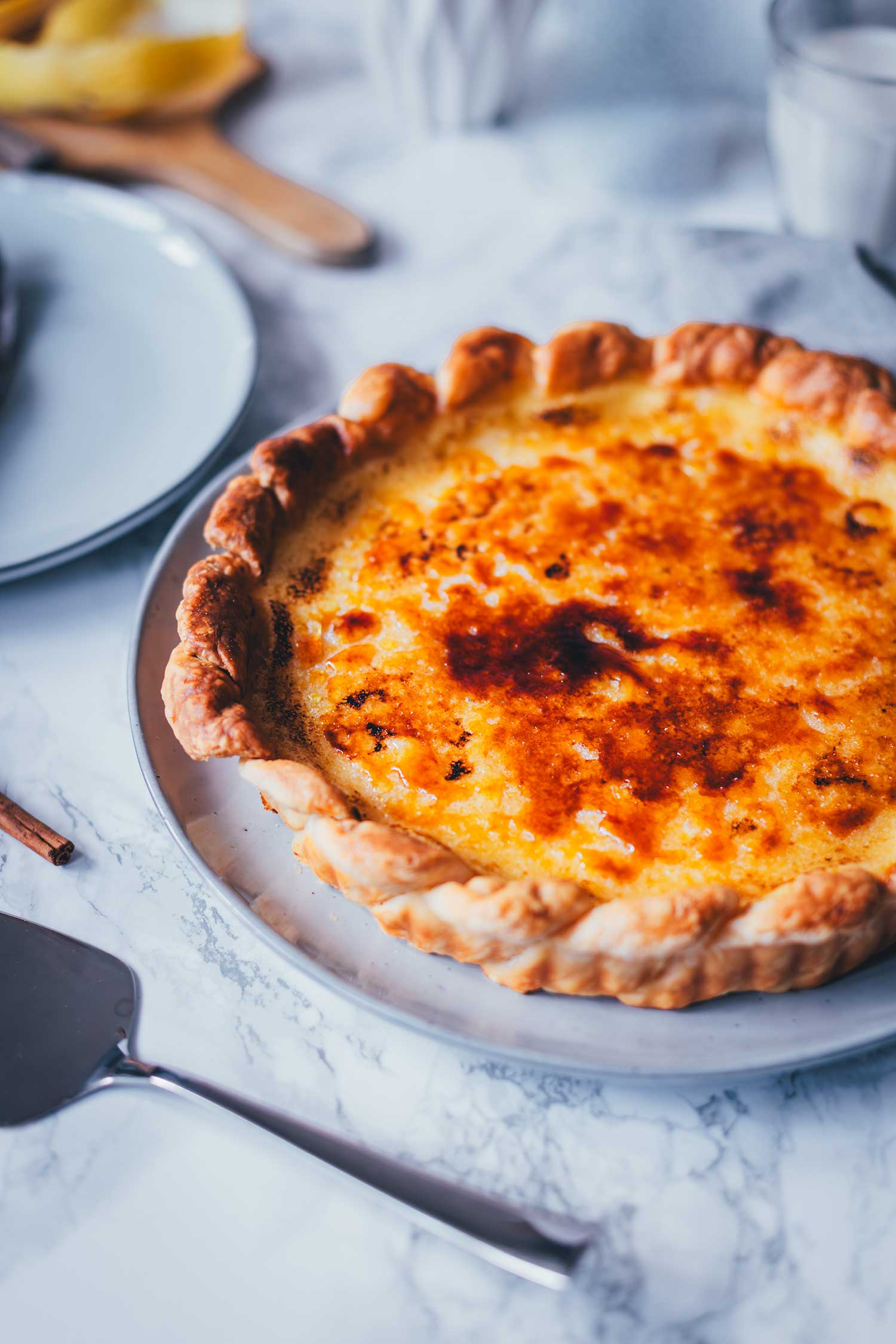 Seitliche Nahaufnahme einer frisch gebackenen Pasteis de Nata Tarte mit knuspriger Zuckerkruste.