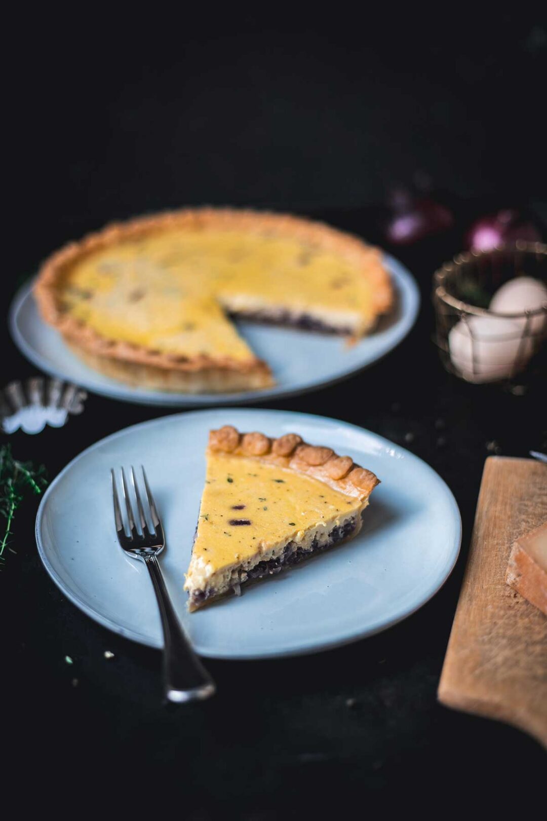 Stück Zwiebelquiche auf Teller im Fokus, im Hintergrund unscharf die restliche Quiche auf Teller sichtbar | moeyskitchen.com