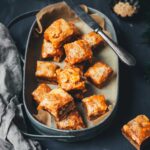 Lebkuchen-Karamell-Würfel in einer Metallschale, Nahaufnahme mit sichtbarer Karamellschicht und Erdnüssen.