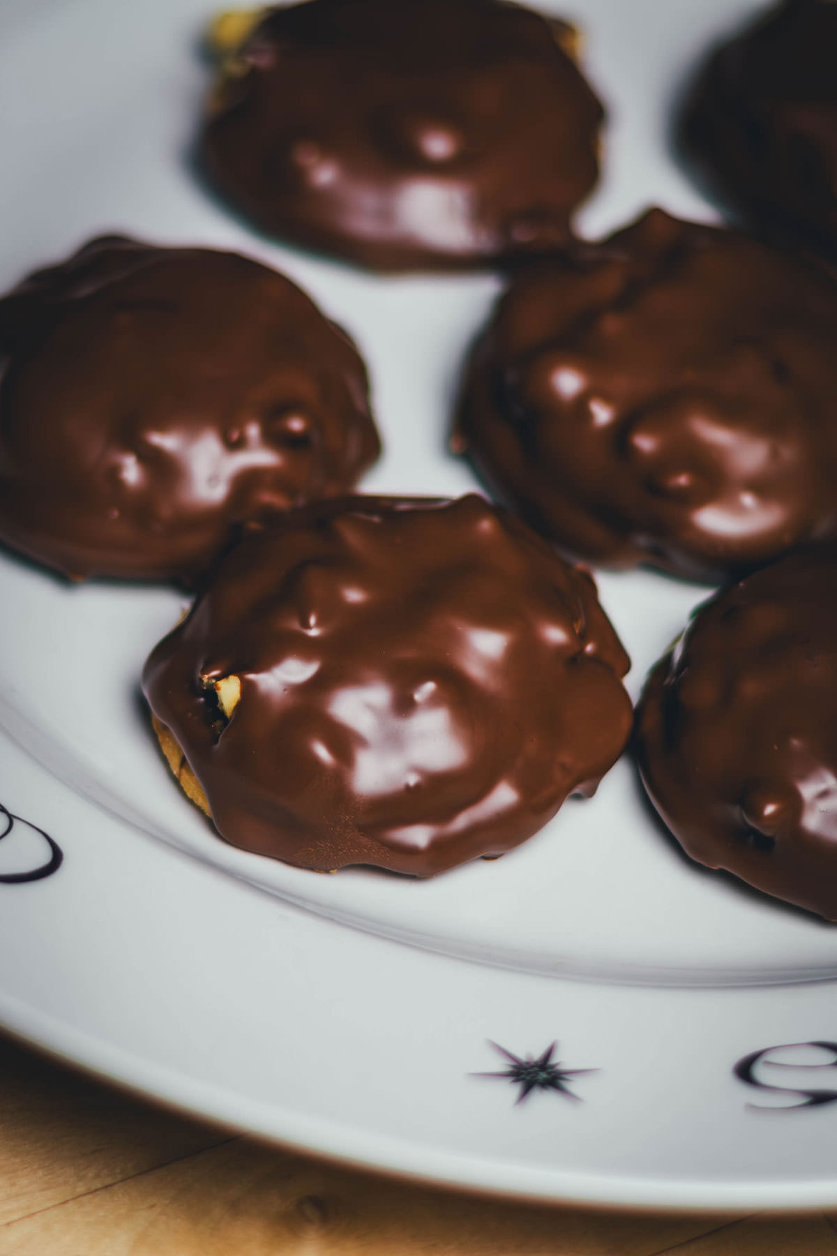 Mit Schokolade überzogene Nougat-Taler mit Haselnüssen als weihnachtliches Plätzchen auf einem Teller.