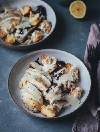 Servierfertiger Radicchio Caesar Chicken Salad auf einem Teller mit Parmesanspänen und Dressing.