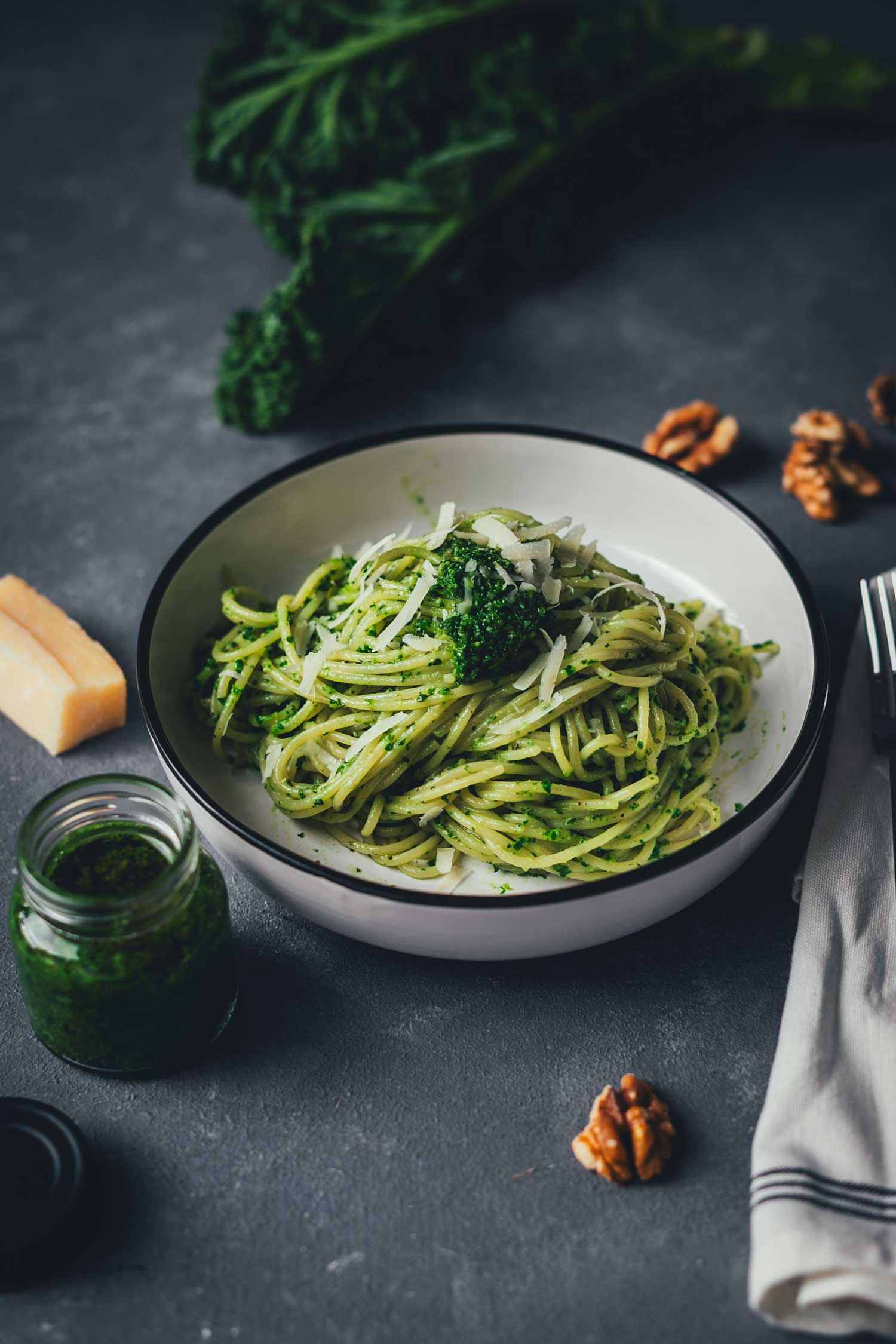 Pasta mit Grünkohl-Pesto in einer Schale, Walnüsse im Hintergrund