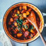 Topshot in einen großen, gusseisernen Topf, der gefüllt mit einem leckeren spanischen Kartoffel-Paprika-Eintopf ist. | moeyskitchen.com