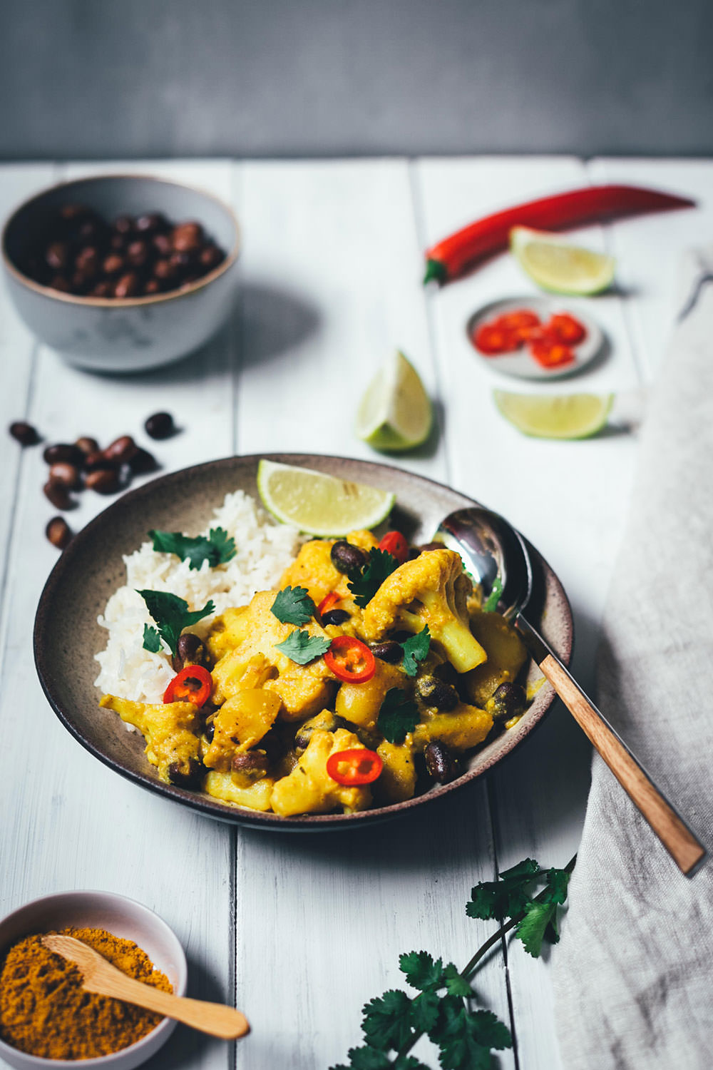 Rezept für ein würziges Blumenkohl-Kartoffel-Curry mit Ackerbohnen. Heimischer Gemüseeintopf, der an indisches Aloo Gobi bzw. Aloo Gobhi erinnert. Ackerbohnen als regionale Körnerleguminosen sind eine tolle Proteinquelle und außerdem ballaststoffreich. Und eine tolle heimische Alternative zu Kichererbsen und anderen Hülsenfrüchten. Perfekt für vegetarische und gesunde Gerichte. Madras Curry, Ingwer und Knoblauch sorgen für Würze, Chili außerdem für etwas Schärfe. Hier gibt es das einfache und unkomplizierte Rezept zum Nachkochen! | moeyskitchen.com