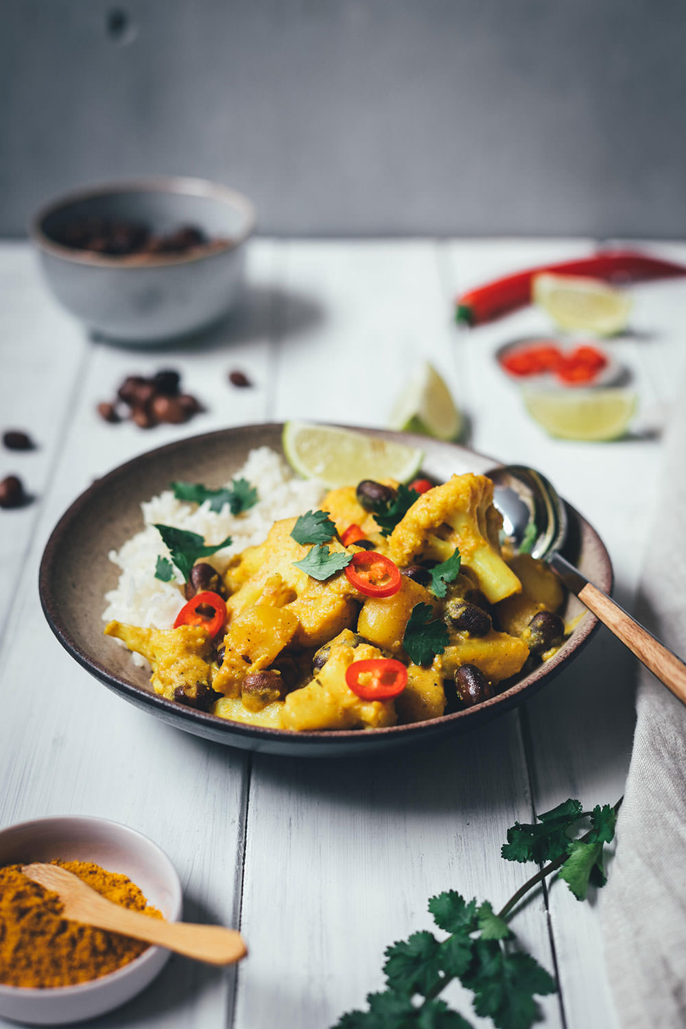 Rezept für ein würziges Blumenkohl-Kartoffel-Curry mit Ackerbohnen. Heimischer Gemüseeintopf, der an indisches Aloo Gobi bzw. Aloo Gobhi erinnert. Ackerbohnen als regionale Körnerleguminosen sind eine tolle Proteinquelle und außerdem ballaststoffreich. Und eine tolle heimische Alternative zu Kichererbsen und anderen Hülsenfrüchten. Perfekt für vegetarische und gesunde Gerichte. Madras Curry, Ingwer und Knoblauch sorgen für Würze, Chili außerdem für etwas Schärfe. Hier gibt es das einfache und unkomplizierte Rezept zum Nachkochen! | moeyskitchen.com