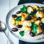 Rezept für gerösteten Blumenkohl aus dem Ofen. So gart der Kohl knusprig und dank asiatisch-orientalischer Gewürze auch lecker würzig! Serviert wird der Blumenkohl auf einer Bohnen-Creme aus weißen Bohnen, die mit griechischem Joghurt, Knoblauch und Zitronensaft verfeinert wird. Dazu gibt es gehackte Petersilie und leckere Kalamata-Oliven. Eine vegetarische Vorspeise oder Mezze, die lauwarm oder bei Raumtemperatur schmeckt. | moeyskitchen.com