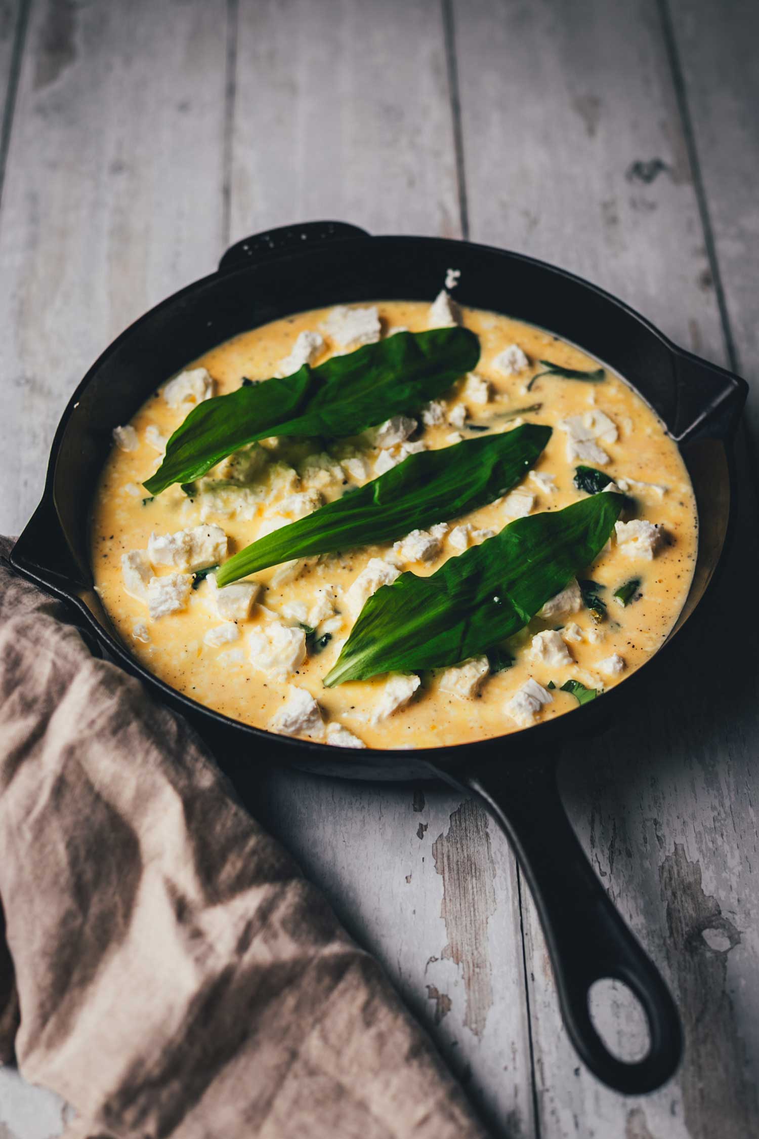 Seitliche Ansicht der Pfanne mit den Zutaten für Bärlauch-Frittata, auf dem Weg in den Ofen