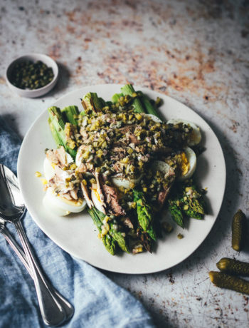 Rezept für würzigen Spargelsalat aus ofengeröstetem grünen Spargel mit einer Kapern-Vinaigrette, Sardinen und Ei. Blitzschnell auf dem Tisch und mit knusprigem Brot und einem Glas kühlen Weißwein perfekt für laue Frühlings- oder Sommerabende auf dem Balkon! Würzige Kapern, Cornichons und Schalotten geben der Vinaigrette Pfiff und harmonieren fantastisch zu den Ölsardinen aus der Dose und dem hart gekochten Ei | moeyskitchen.com