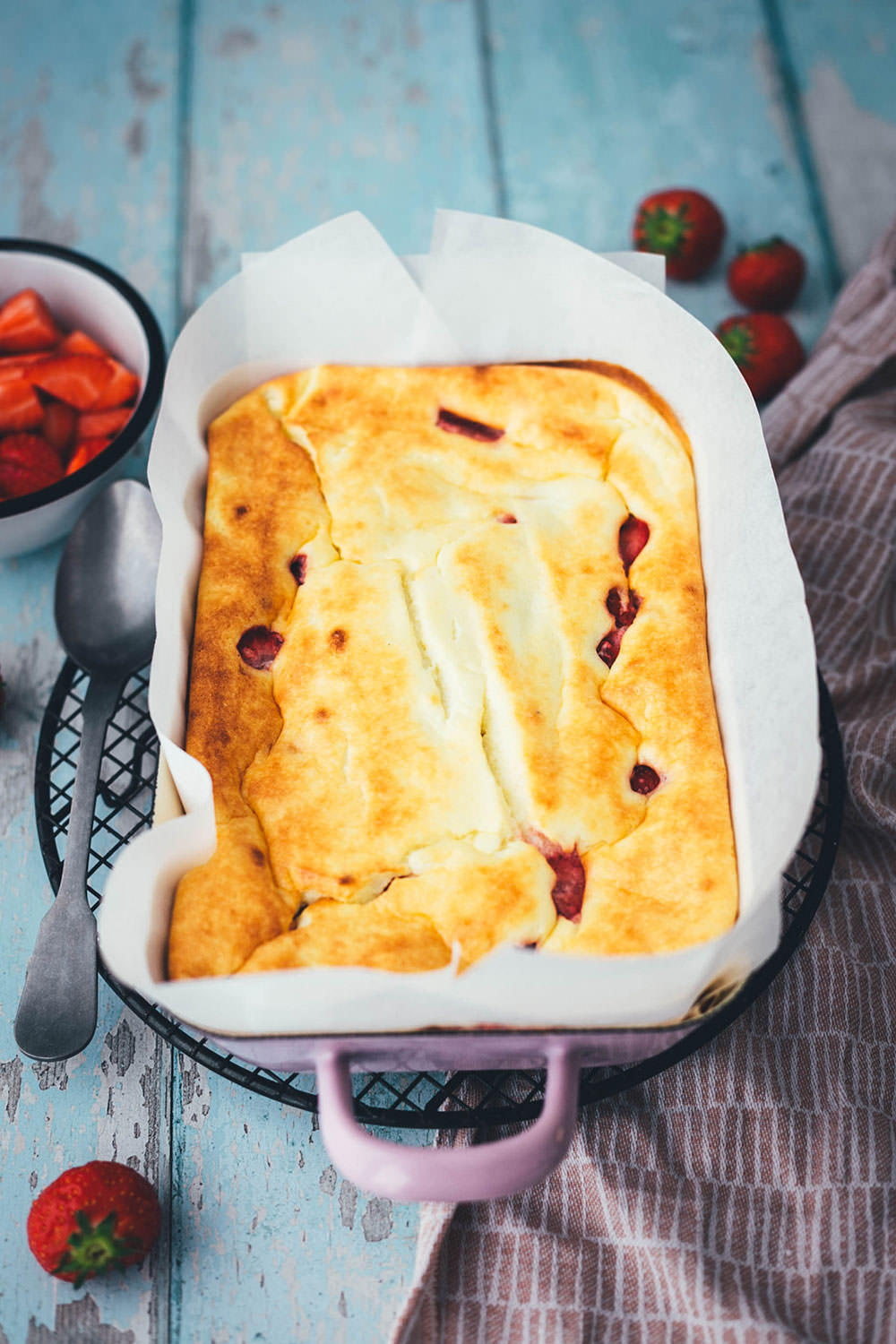 Rezept für luftigen Quark-Auflauf mit Erdbeeren. Leckeres, nicht zu süßes Dessert oder Frühstück für die ganze Familie! Magerquark wird dazu einfach mit Ei und Grieß locker aufgeschlagen und dann mit Erdbeeren in einer Auflaufform gebacken. Anschließend lauwarm mit frischen Erdbeeren serviert, so dass es an einen leckeren, aber unheimlich einfachen Käsekuchen erinnert. | moeyskitchen.com