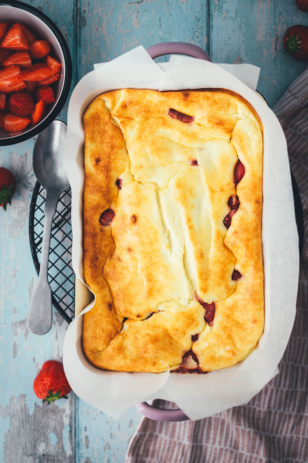 Rezept für luftigen Quark-Auflauf mit Erdbeeren. Leckeres, nicht zu süßes Dessert oder Frühstück für die ganze Familie! Magerquark wird dazu einfach mit Ei und Grieß locker aufgeschlagen und dann mit Erdbeeren in einer Auflaufform gebacken. Anschließend lauwarm mit frischen Erdbeeren serviert, so dass es an einen leckeren, aber unheimlich einfachen Käsekuchen erinnert. | moeyskitchen.com