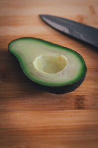 Halbierte reife Avocado auf einem Holzbrett, bereit zum Würfeln für den Cobb Salad.