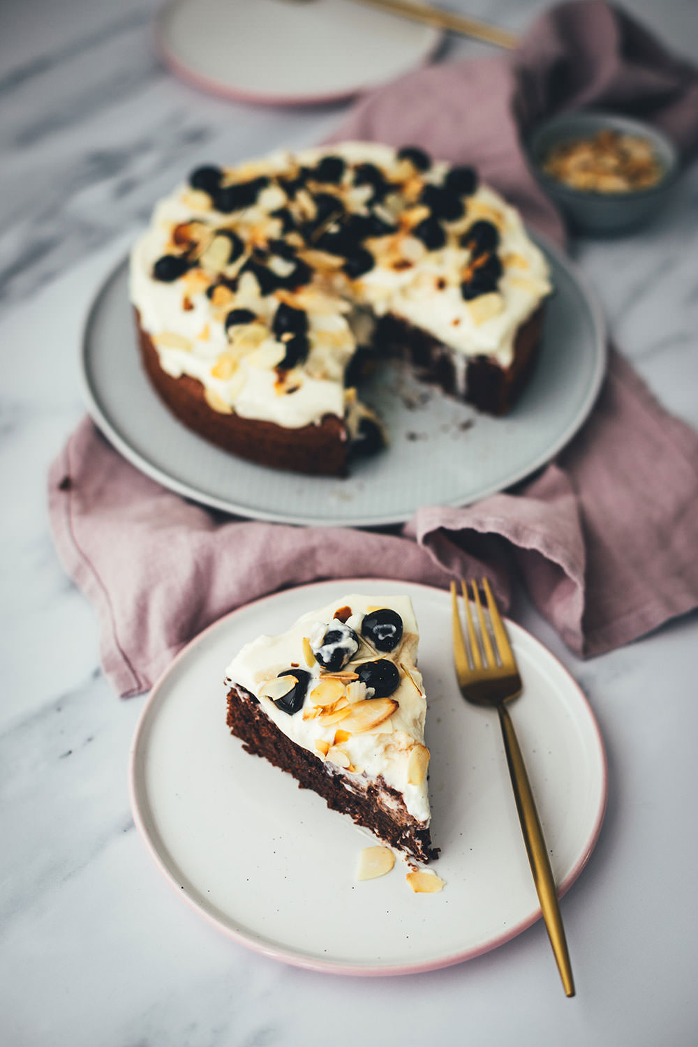 Der italienische Kuchenklassiker in neuem Gewand: Torta Caprese ist ein super saftiger Schokoladenkuchen, der ganz ohne Mehl auskommt. Stattdessen kommen hier zerkleinerte, geröstete Mandeln in den Teig. Und statt die Torta Caprese wie im Original nur mit Puderzucker zu bestreuen, serviere ich sie hier mit einer wunderbaren Mascarpone-Creme, leckeren Amarenakirschen und zusätzlich mit gerösteten Mandelblättchen. Der saftigste Schokokuchen überhaupt! | moeyskitchen.com