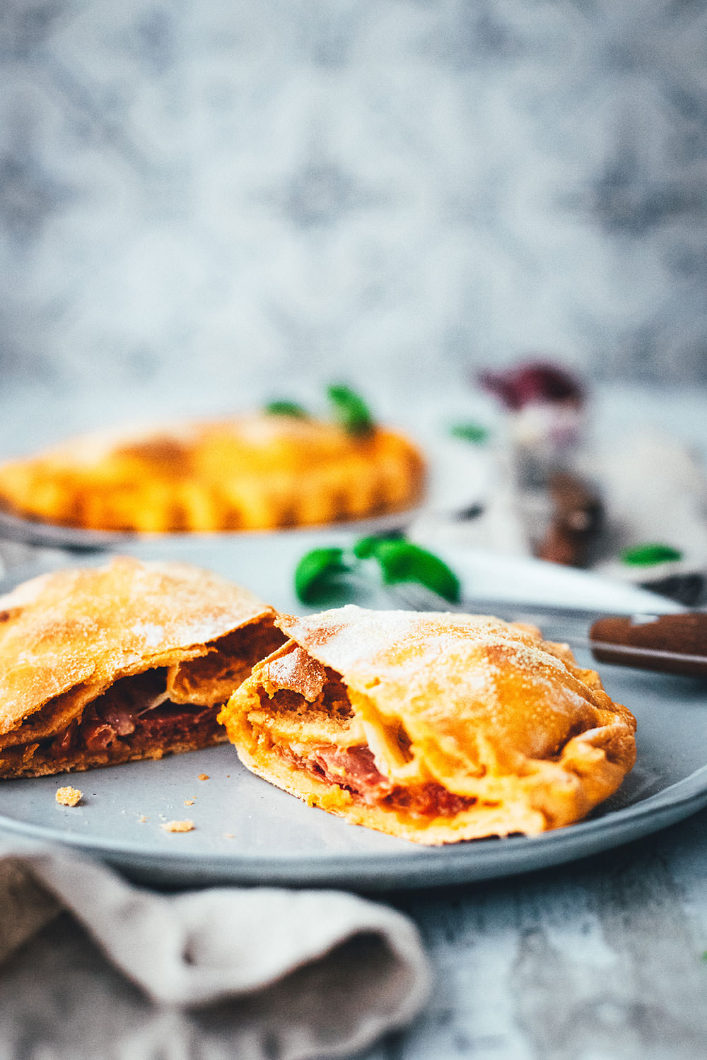 Rezept für knusprige Calzone – italienische Pizza, die als Pizzatasche gebacken wird. Mit leckerer Füllung aus Tomatensauce, Mozzarella, Schinken und Salami. Lässt sich super vorbereiten, einfrieren und frisch genießen. Ganz easy zu Hause selber machen und im normalen Ofen backen! | moeyskitchen.com