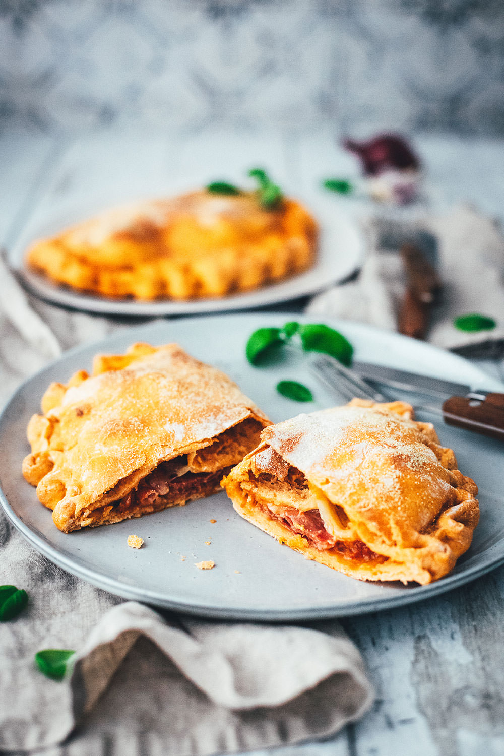 Rezept für knusprige Calzone – italienische Pizza, die als Pizzatasche gebacken wird. Mit leckerer Füllung aus Tomatensauce, Mozzarella, Schinken und Salami. Lässt sich super vorbereiten, einfrieren und frisch genießen. Ganz easy zu Hause selber machen und im normalen Ofen backen! | moeyskitchen.com