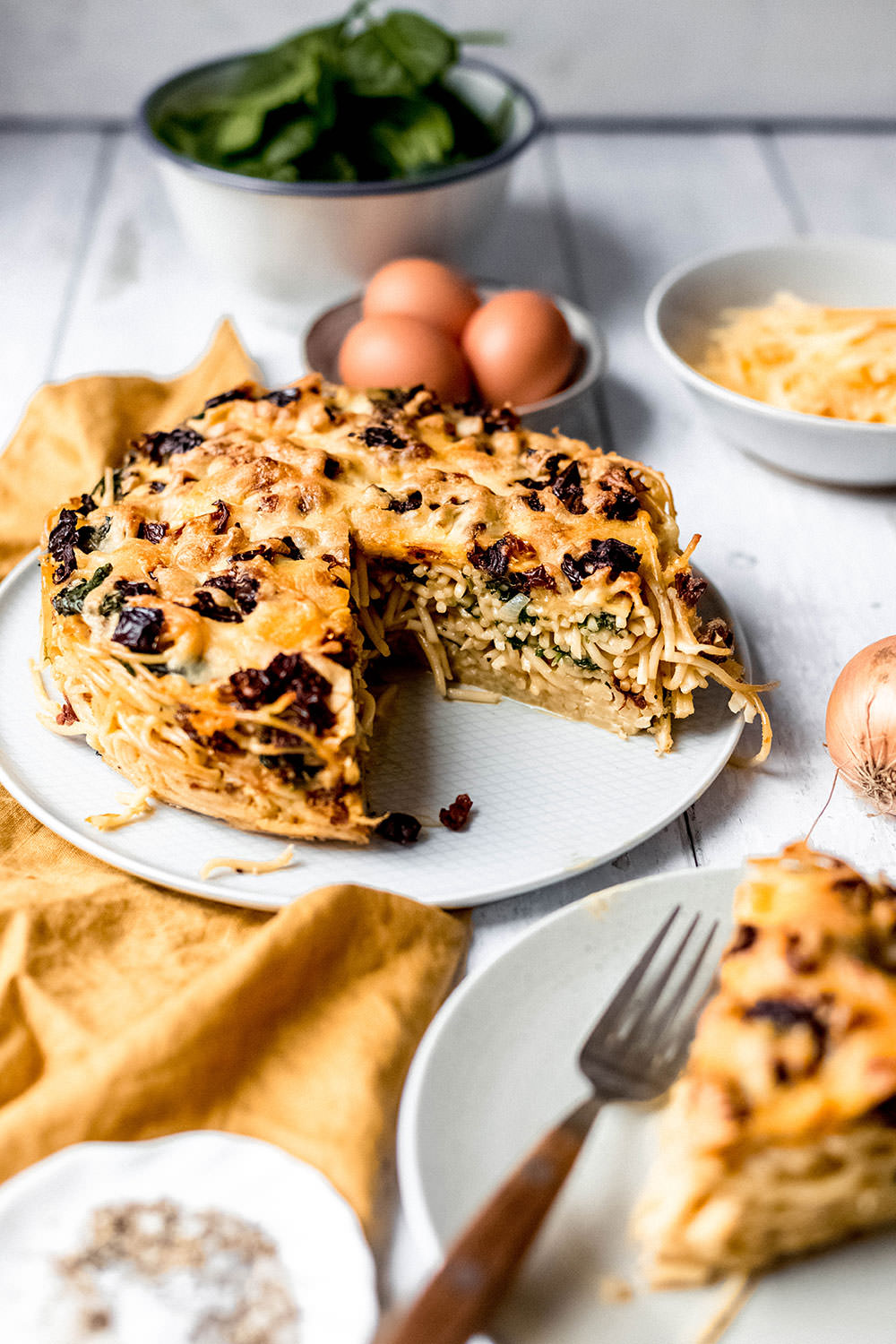 Rezept für herzhaften Spaghetti-Kuchen. Vegetarischer Nudelauflauf mit frischem Spinat und getrockneten Tomaten. Gebacken in einer Spingform und serviert in Form von Kuchenstücken | moeyskitchen.com