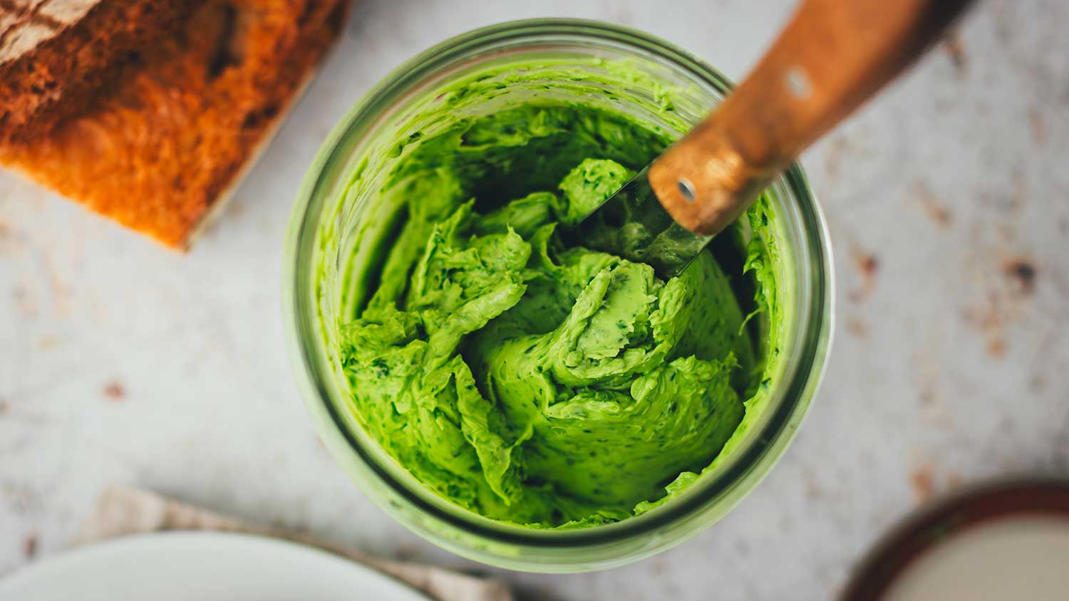 Topshot Nahaufnahme von einem Glas mit frisch aufgeschlagener, cremiger Bärlauchbutter.