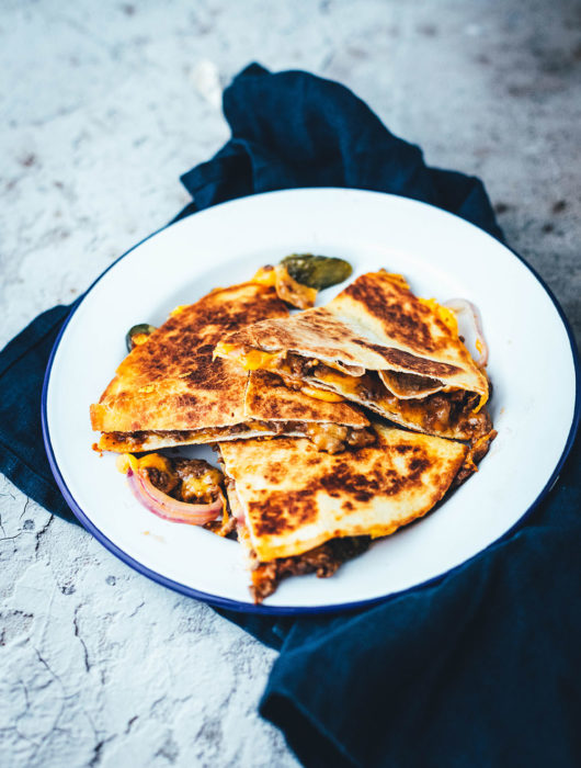 Rezept für saftige Cheeseburger Quesadillas! Das sind leckere Quesadillas mit einer Füllung aus Hackfleisch oder einer vegetarischen Hackfleisch-Alternative, reichlich Cheddar, roten Zwiebeln und Gewürzgurken. Blitzschnell zubereitet aus einfachen und ehrlichen Zutaten und so lecker! Als Vorspeise oder Hauptgericht und mit Dip serviert | moeyskitchen.com