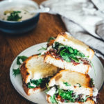 Rezept für veganes Hummus-Sandwich: knuspriges Brot mit selbst gemachtem weißen Bohnen-Hummus, karamellisierten Zwiebeln und getrockneten Tomaten. Mit Rucola und Petersilie verfeinert und zum Mittagessen oder als Stulle für unterwegs serviert. Eine vegane Alternative zum klassischen Butterbrot! | moeyskitchen.com