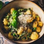 Gnocchi Pfanne Rezept mit Spinat und Pesto – fertig serviert in einer Schüssel mit frischem Basilikum und Parmesan.
