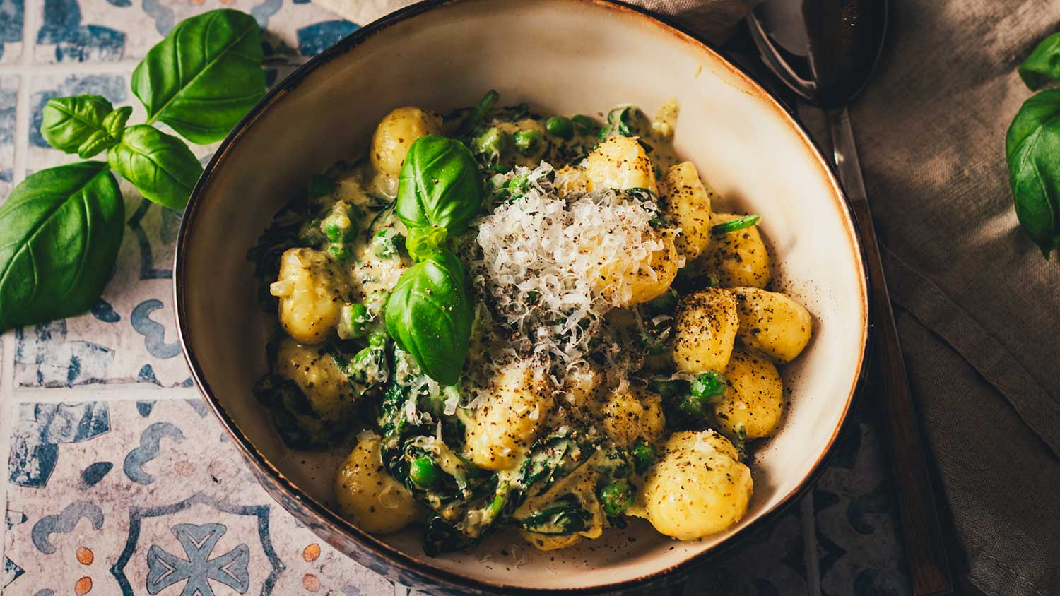 Gnocchi Pfanne Rezept mit Spinat und Pesto – fertig serviert in einer Schüssel mit frischem Basilikum und Parmesan.